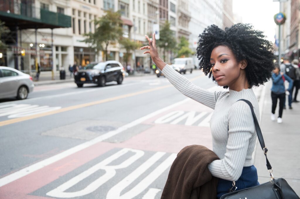 African American woman with curly black hair hailing a cab in New York city